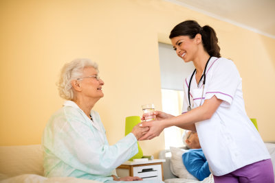 young nurse giving water to senior woman