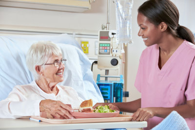 nurse serving meal to a senior woman